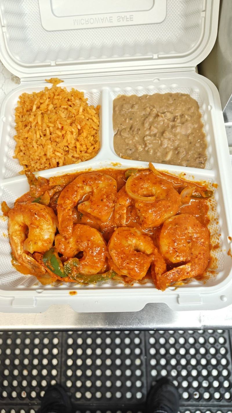 Shrimp in red chile sauce with peppers and onions, served with Mexican rice and refried beans in a takeout container.