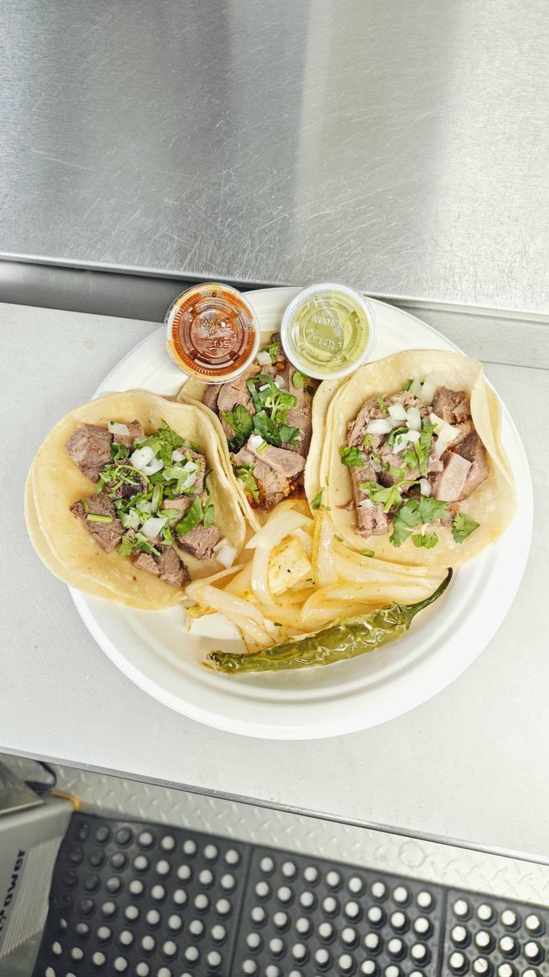 Three soft tacos topped with onion and cilantro, served with fries, a roasted chile and two salsas.